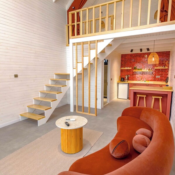 Um interior moderno com uma escada, uma área de cozinha e um espaço de estar com uma mesa redonda.