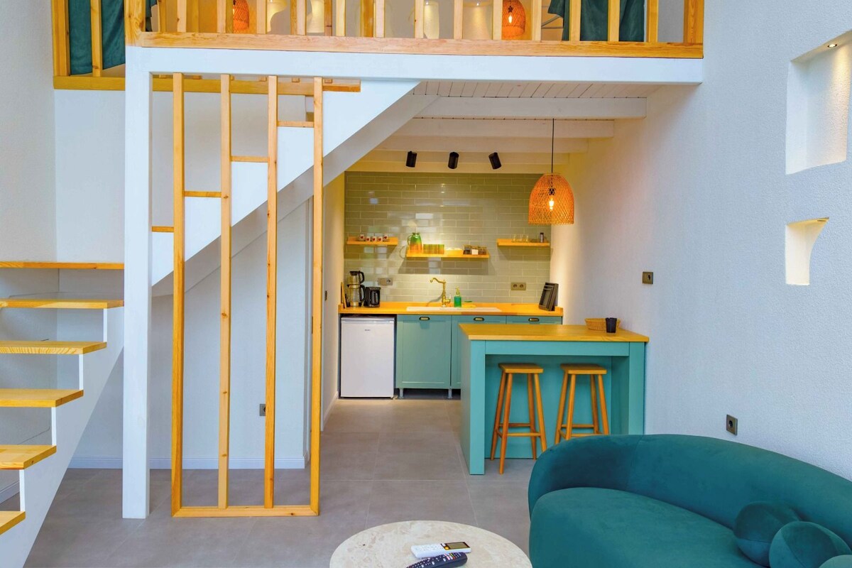 Ein Loft-Wohnraum mit Küche, Treppe und einer Couch.