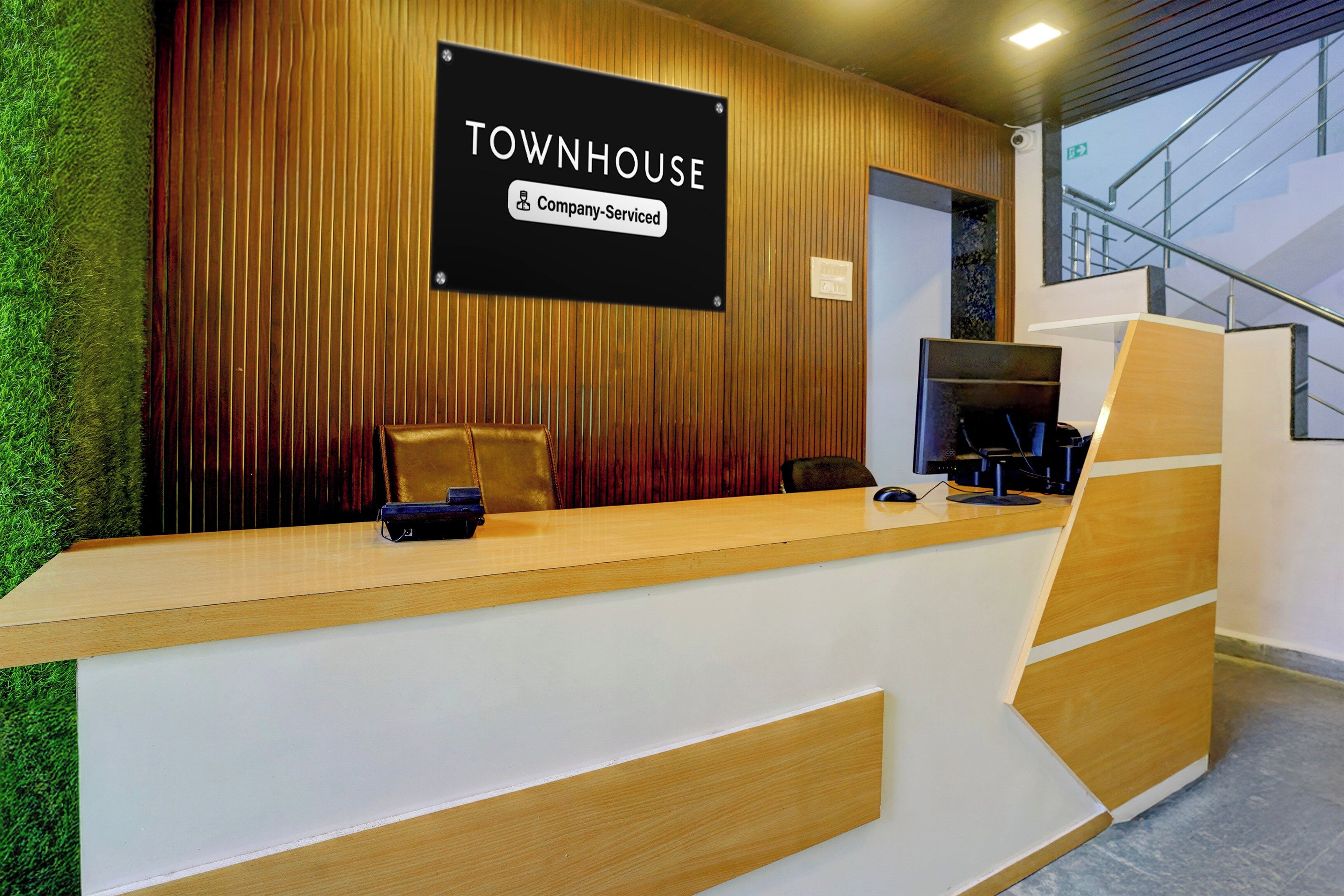 Una mesa de recepción con un cartel que dice 'TOWNHOUSE Company-Serviced' y una computadora.