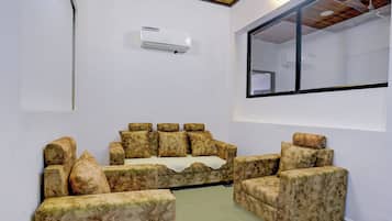 Una habitación con sofá, ventana y equipo de aire acondicionado.