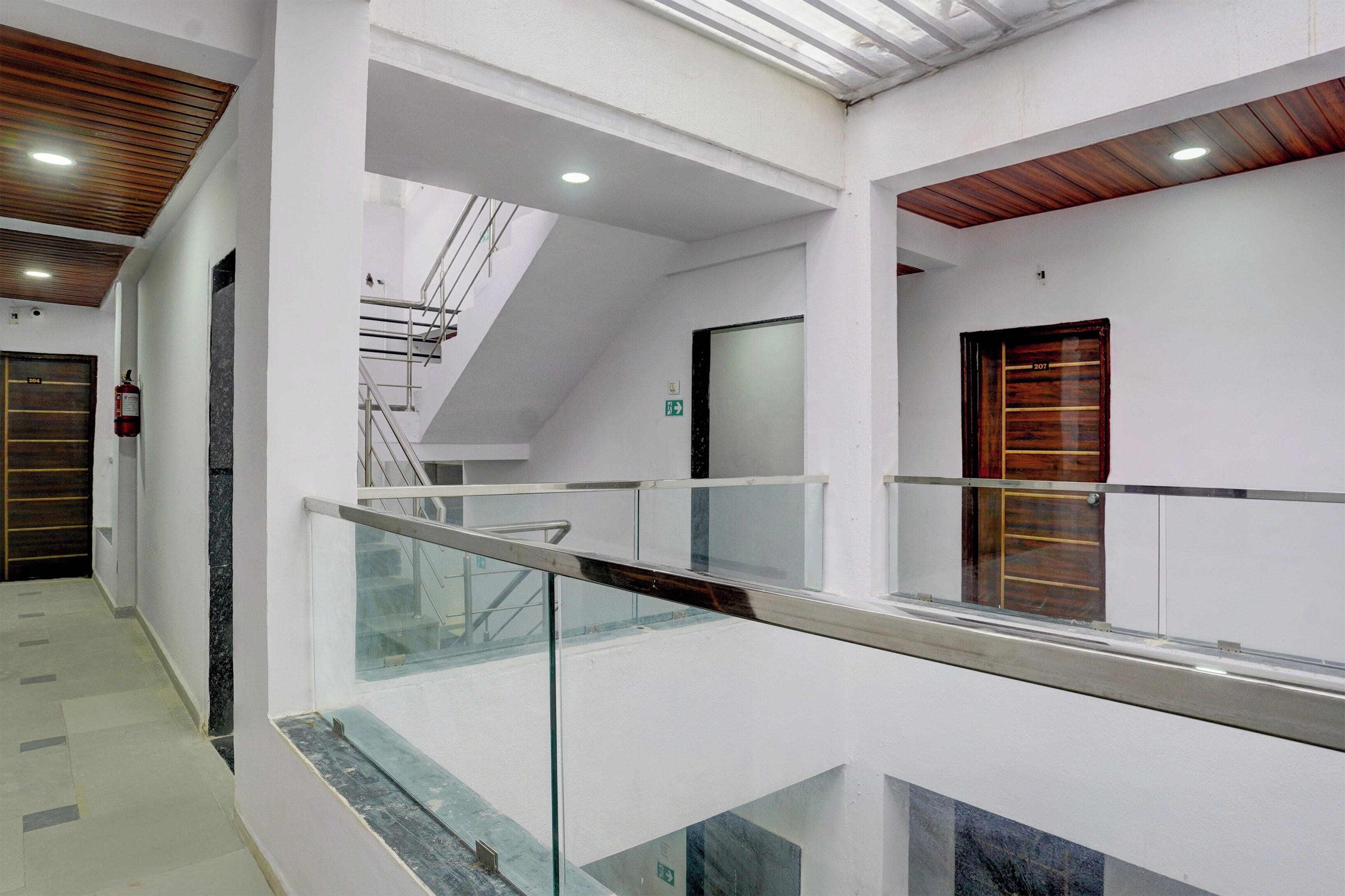 Un interior moderno con barandilla de vidrio, una puerta de madera y una escalera.