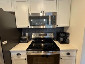 A kitchen with a stainless steel microwave, a stove, a toaster, and a Keurig coffee maker. - Northern Oasis near Nub's Nob (Pleasantview Township)