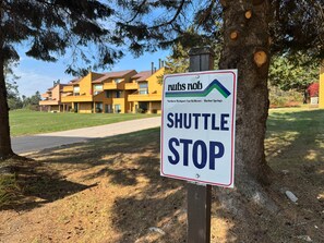 A sign indicating a shuttle stop with a building in the background. - Northern Oasis near Nub's Nob (Pleasantview Township)