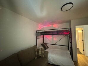 A room with bunk beds, a sofa, and a ceiling with a starry light projection. - Northern Oasis near Nub's Nob (Pleasantview Township)