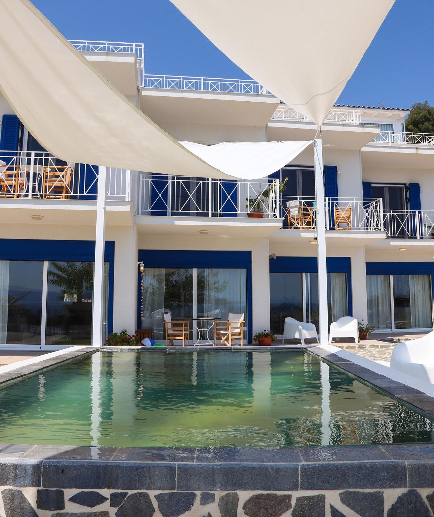 Un hotel de varios pisos con piscina, zona de estar exterior y balcones.