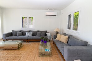 Een moderne woonkamer met een grijze bank, een glazen salontafel en een lamp.