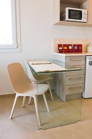 Una kitchenette equipada con microondas, un refrigerador pequeño y un armario con utensilios de cocina.