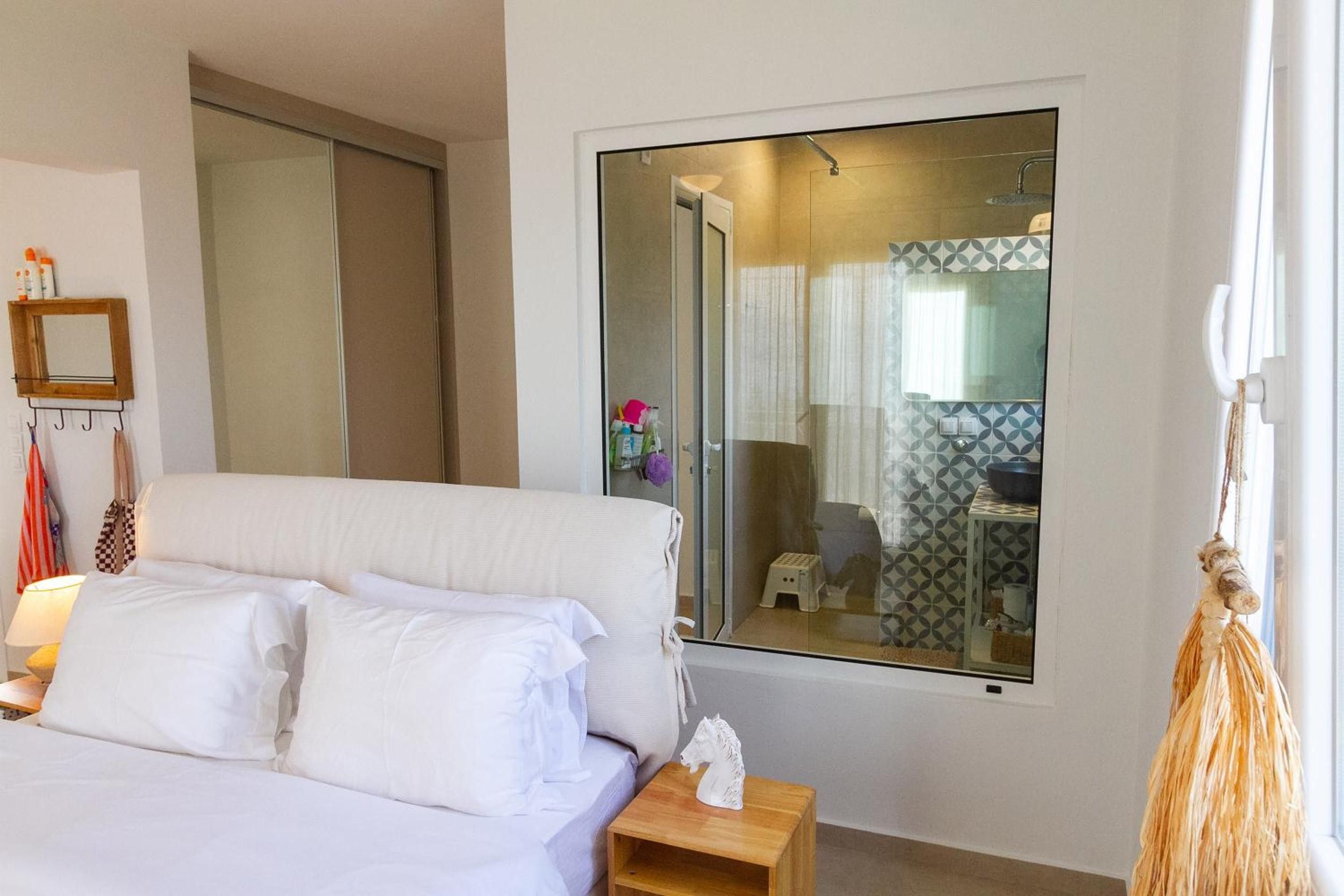Een hotelkamer met een bed, nachtkastje, spiegel en uitzicht op de badkamer.
