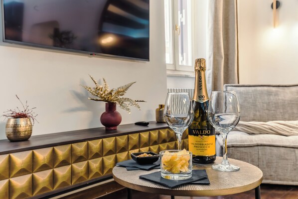 A round table with a bottle of Valdo wine, two wine glasses, a bowl of snacks, and a small vase with dried plants. - New Listing (Roma)