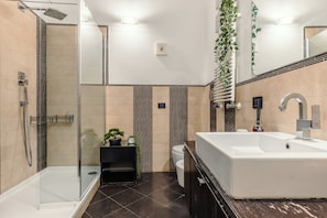 Un baño moderno con ducha envuelta en vidrio, una bañera blanca grande y un inodoro.