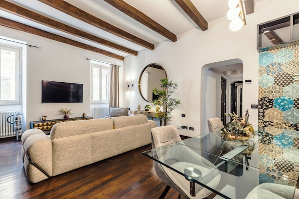 Una sala de estar moderna con un sofá, una mesa de comedor de vidrio y un espejo grande.