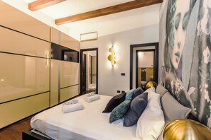 A modern bedroom with a bed, a wardrobe, and a bathroom visible through an open door. - New Listing (Roma)