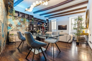 Una sala de estar moderna con una mesa de centro de vidrio, sillas tapizadas en gris y piso de madera.