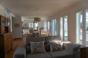 A spacious living room with a sofa, a dining area with chairs and a table, and large windows allowing natural light. - Casa Perdiz, ideal choice for style and comfort (Conil de la Frontera)
