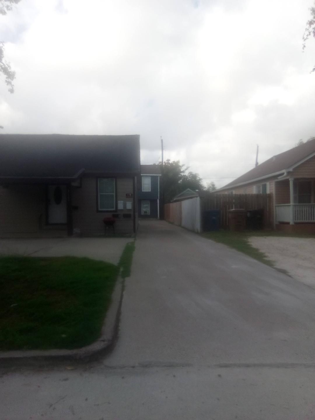 A residential street with houses, a clear sky, and a grassy area.