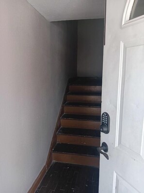 A staircase with wooden steps leading to a white door with a keypad lock. - WESTSIDE 1-bedroom remodelded apt, AC, nice quartz counters- in Corpus Christi (Corpus Christi)