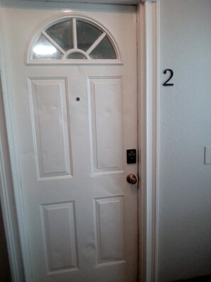 A white door with a small window above it and a doorbell. - WESTSIDE 1-bedroom remodelded apt, AC, nice quartz counters- in Corpus Christi (Corpus Christi)
