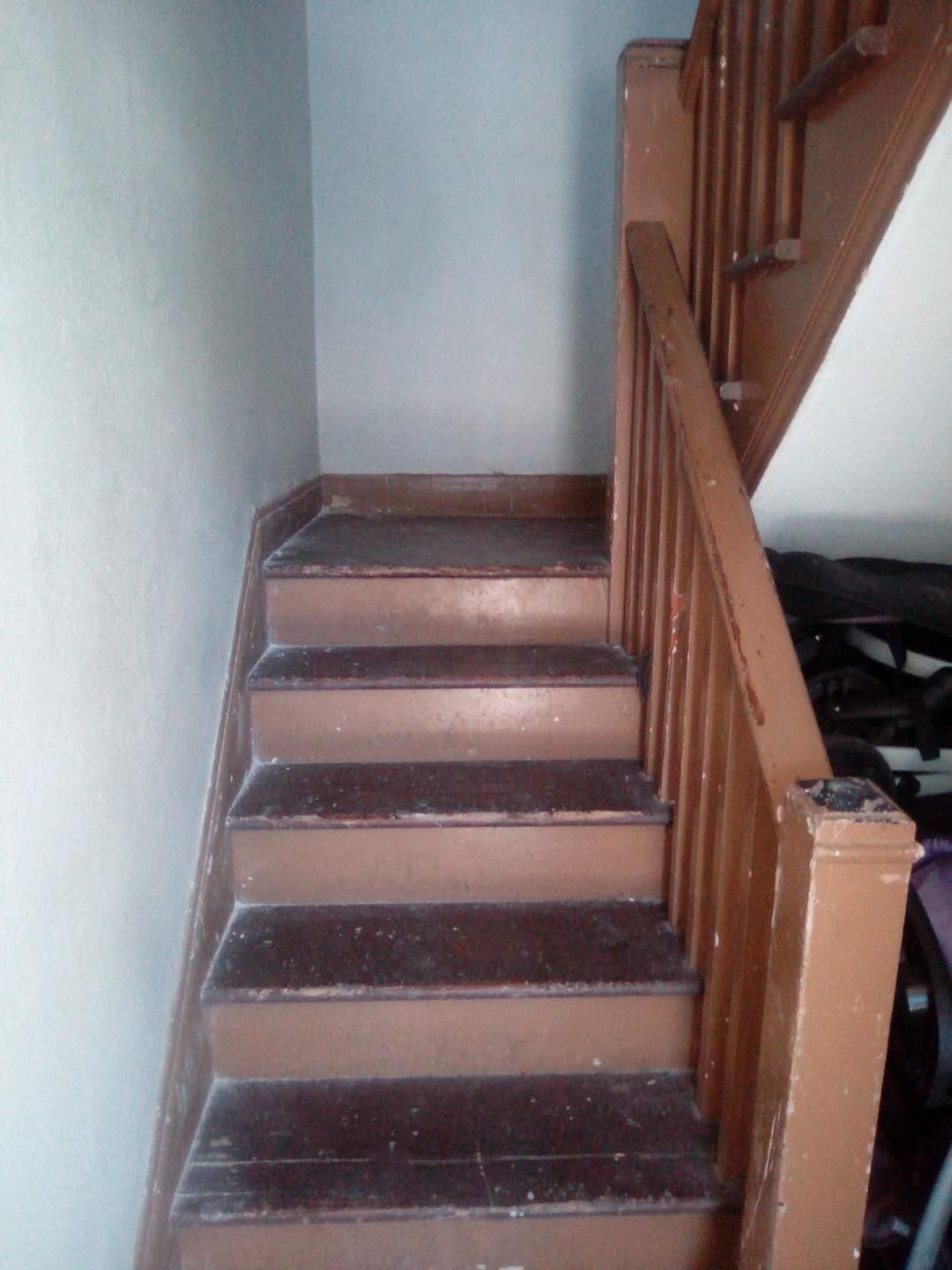 A wooden staircase with a handrail leading to an upper floor.