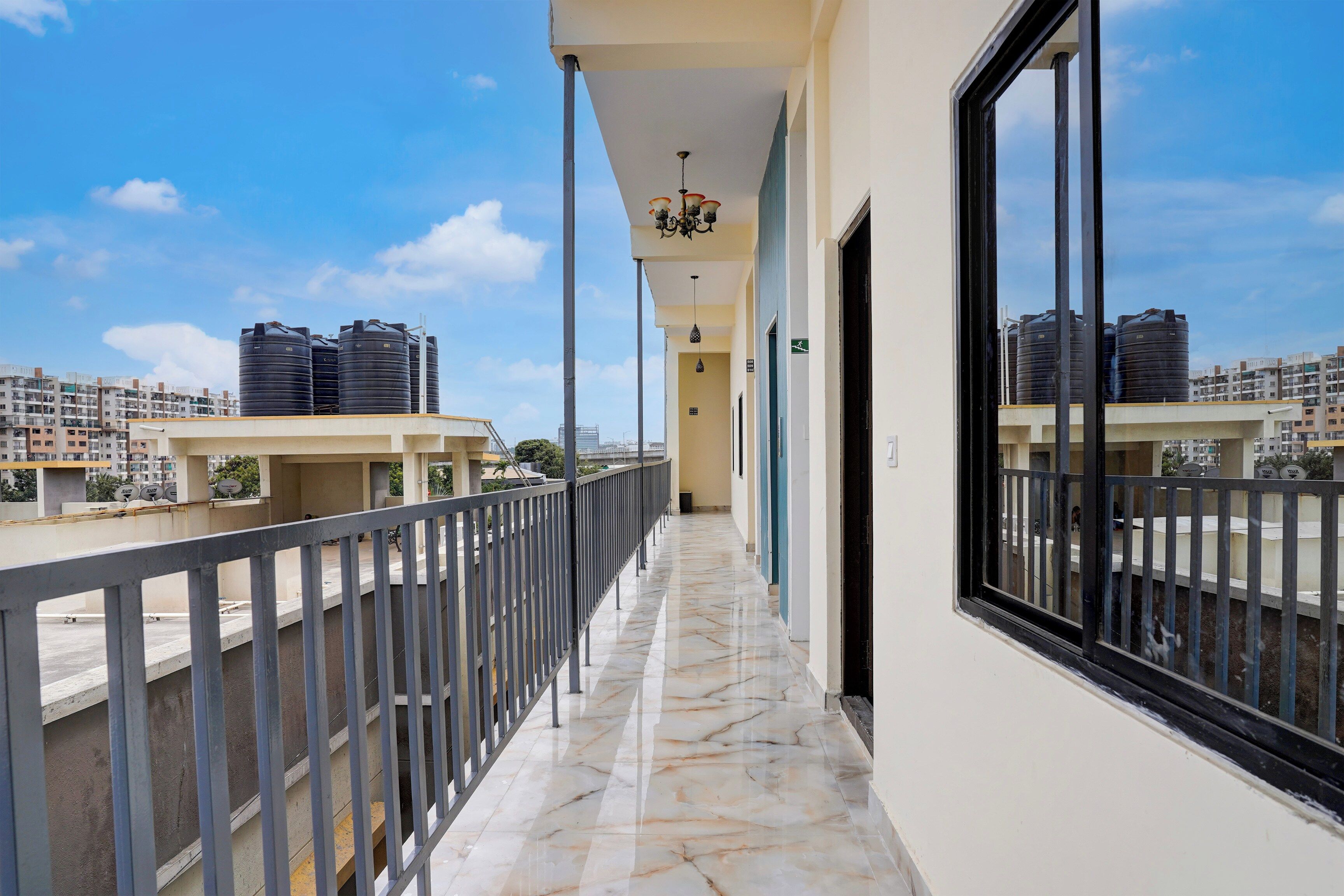 A corridor with a marble floor leading to a balcony with a metal railing.