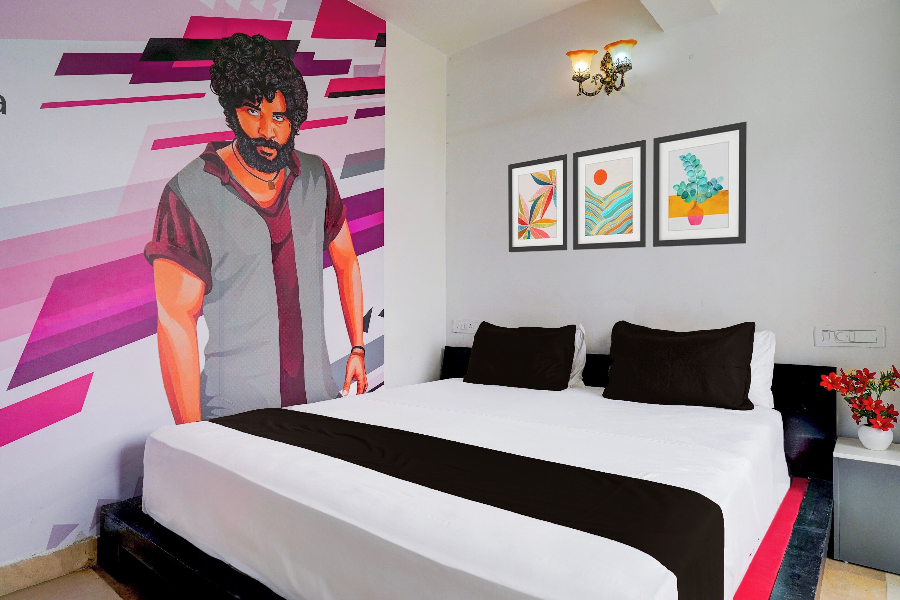 A bedroom with a bed, a wall with a large poster, and three framed artworks.