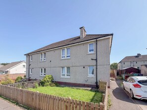 A two-story residential building with a tiled roof and a fenced yard. - Ground Floor 2 Bed Apt in Salsburgh (Salsburgh)