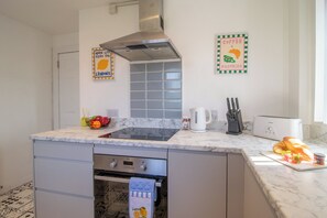 A modern kitchen with a built-in oven, a stainless steel range hood, and a marble countertop. - Ground Floor 2 Bed Apt in Salsburgh (Salsburgh)