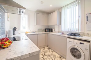 A modern kitchen with a microwave, sink, and Bosch washing machine. - Ground Floor 2 Bed Apt in Salsburgh (Salsburgh)