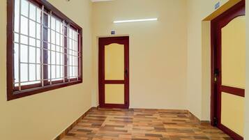 Un pasillo con piso de madera, una ventana con barrotes y una puerta con el símbolo del número.