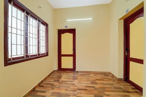 Un pasillo con piso de madera, una ventana con barrotes y una puerta con el símbolo del número.