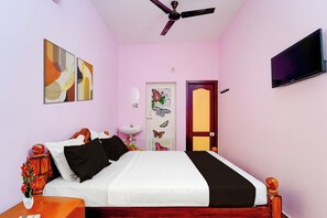 Een slaapkamer met een bed, een televisie, een plafondventilator, een deur met vlinderstickers en een spiegel aan de muur.
