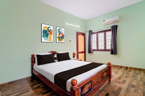 Een hotelkamer met een houten bed, een raam met gordijnen en twee kunstwerken in een lijst aan de muur.