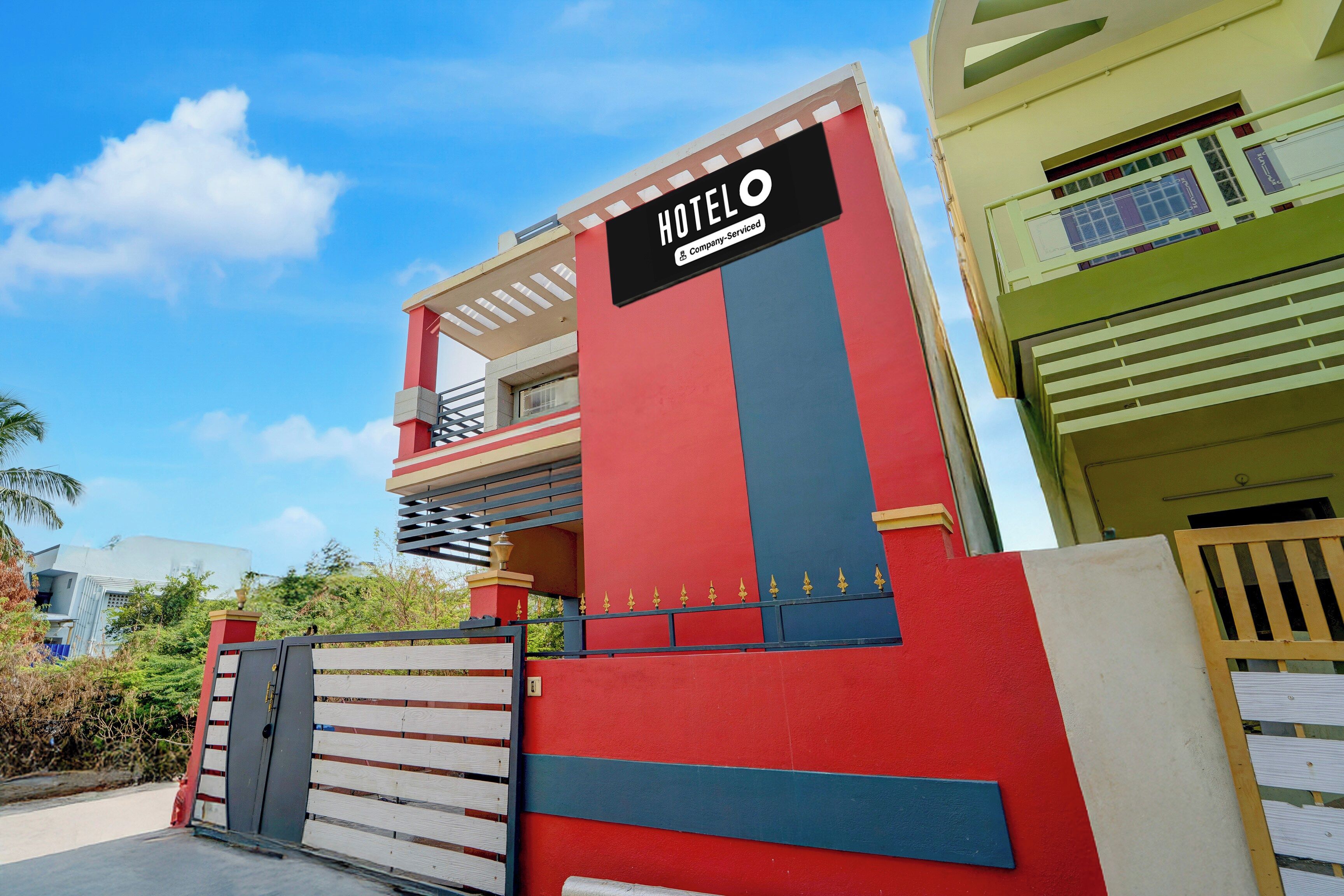 Un hotel con un letrero llamativo, un acceso mediante portón y un balcón.