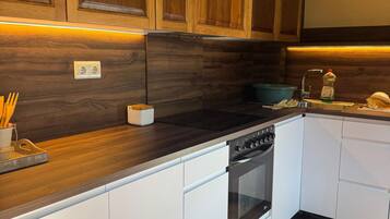 Una cocina moderna con armarios de madera, horno integrado y encimera con utensilios.