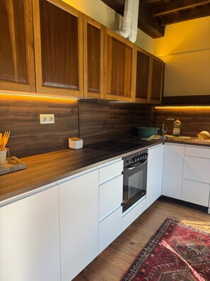 Een moderne keuken met houten kastjes, een inbouwoven en een aanrecht met keukengerei.