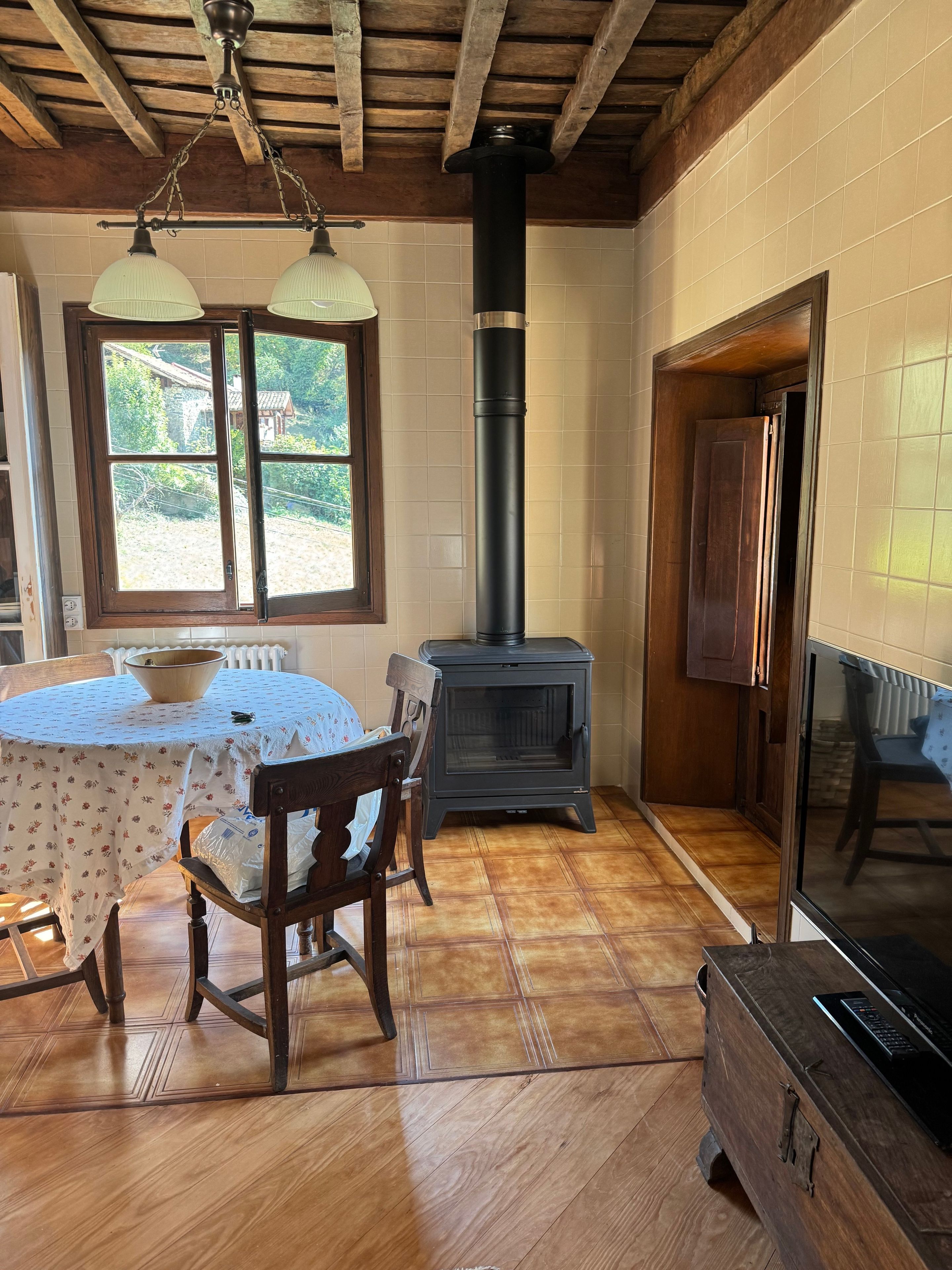 Una habitación con una mesa de madera, sillas, una estufa y un televisor.