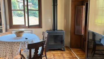 Una habitación con una mesa de madera, sillas, una estufa y un televisor.