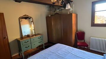 Un dormitorio con una cama grande, un aparador, un espejo, una silla roja y una ventana.