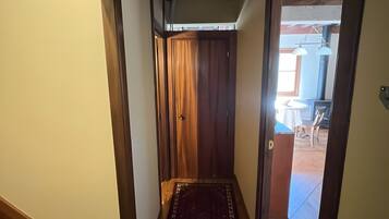 Un pasillo con piso de madera, alfombra estampada y una puerta que da a otra habitación.