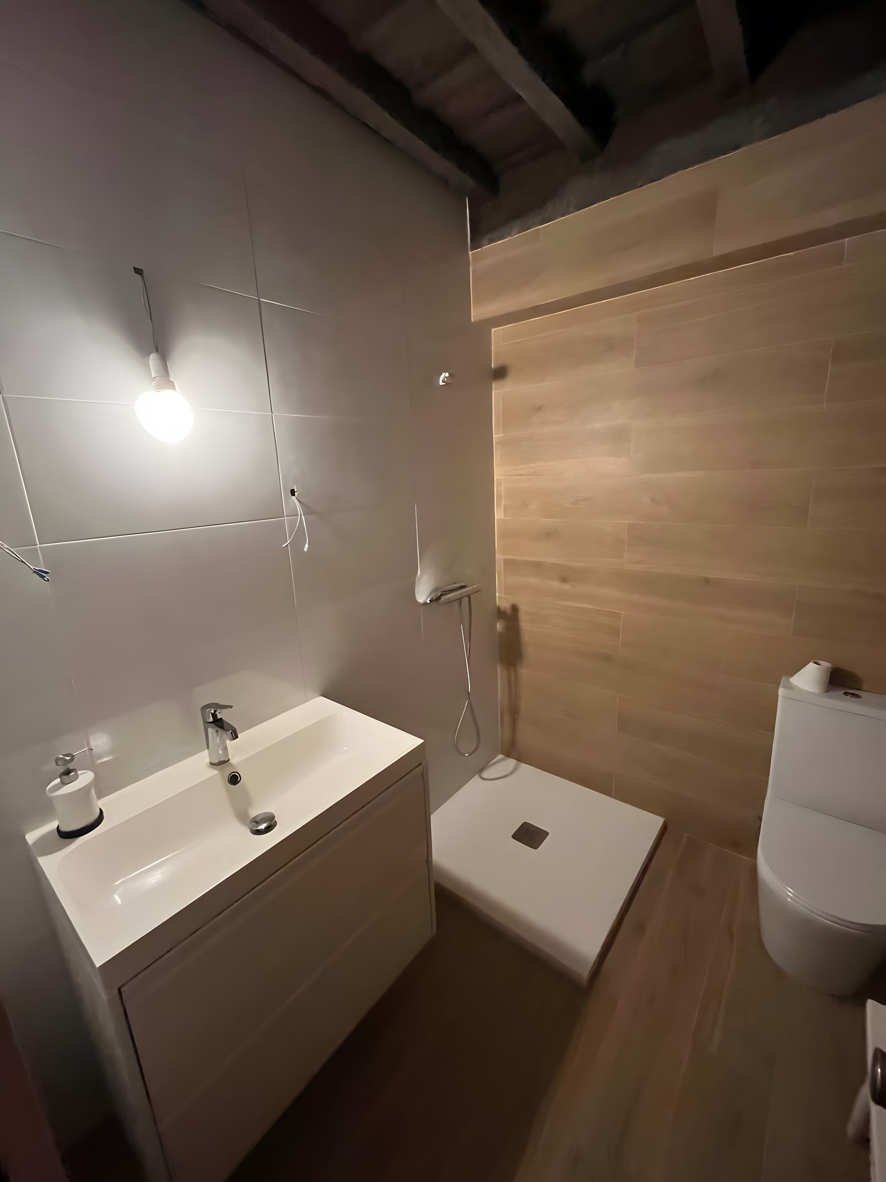 Un baño moderno con lavamanos, espejo y ducha blancos.