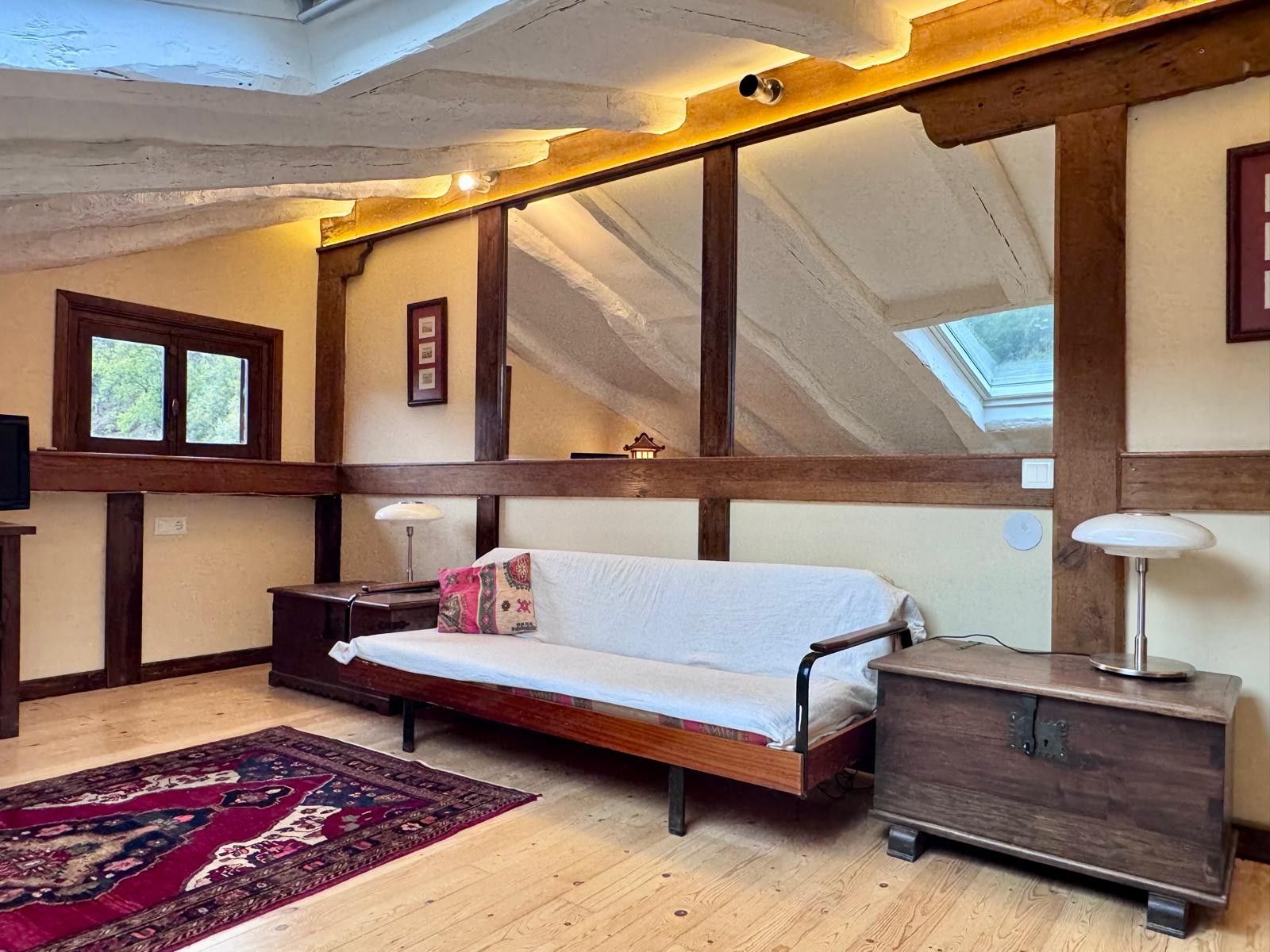 Een gezellige kamer met een houten bed, een nachtkastje, een lamp en een vloerkleed.