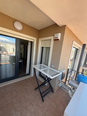 A balcony with a table, a grill, and a view of buildings. - New Listing (Catania)