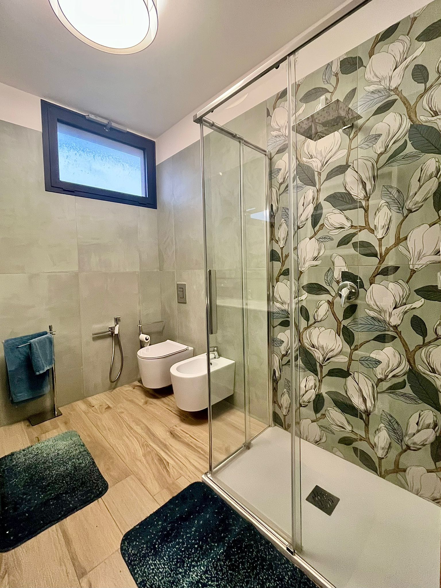 A modern bathroom with a glass shower enclosure, a toilet, and a bidet.