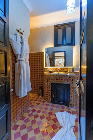 A bathroom with a checkered floor, a sink, a mirror, and two towels hanging on the wall. - RYAD DOTTY (Marrakech)