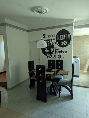 A dining area with a modern table and chairs, a ceiling fan, and a decorative wall with text. - Apartamento 3 hab. cerca al aeropuerto de Neiva · Ideal familias y grupos (Neiva)