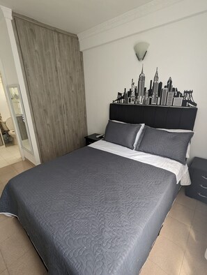 A bedroom with a bed, a wardrobe, a nightstand, and a wall-mounted light fixture. - Apartamento 3 hab. cerca al aeropuerto de Neiva · Ideal familias y grupos (Neiva)