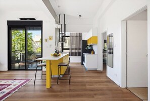A modern kitchen with a yellow island, black chairs, and a dining table. - City Apt • Near Talpiot Market by SeaNRent (Haifa)