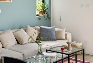 A living room with a sofa, a glass coffee table, a vase with a plant, a candle, and a remote control. - City Apt • Near Talpiot Market by SeaNRent (Haifa)