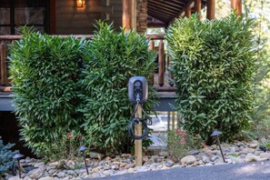 A landscaped garden with neatly trimmed bushes, a wooden post with a charging station, and a stone pathway. - Smokey Mountain Splendor: Sauna, Pickleball, Game Room & Jacuzzi (Sevierville)