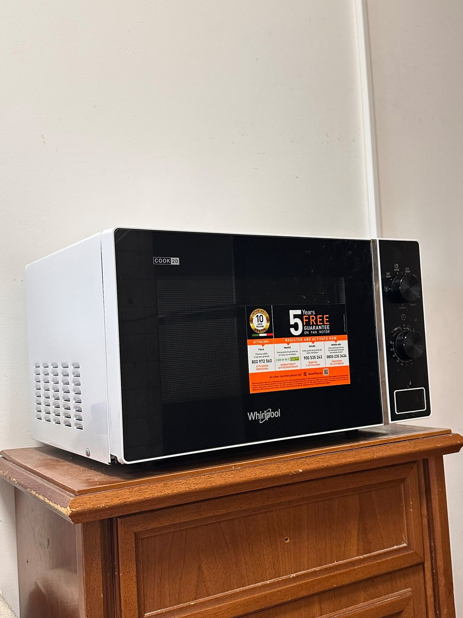 A white microwave on a wooden cabinet.