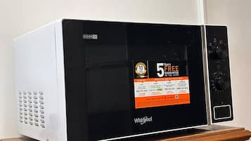A white microwave on a wooden cabinet.